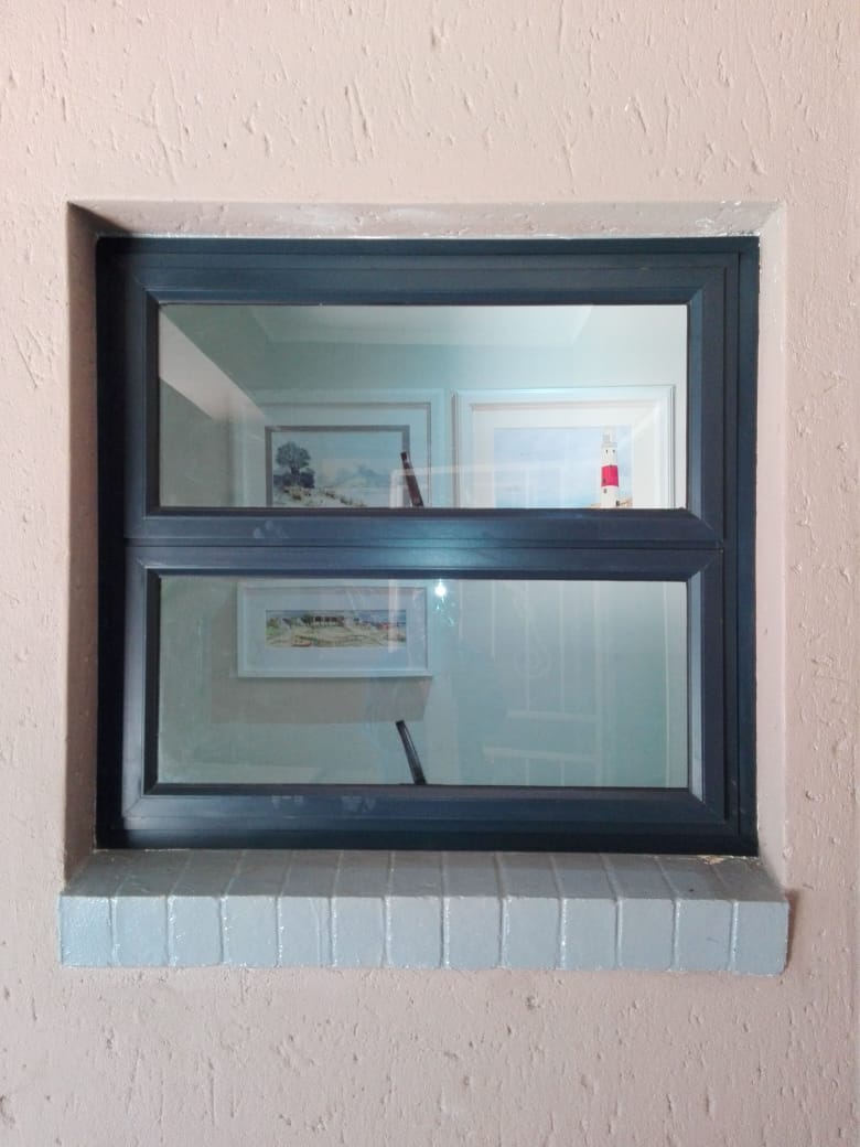 Compact dark aluminium top-hung window installed in an interior wall