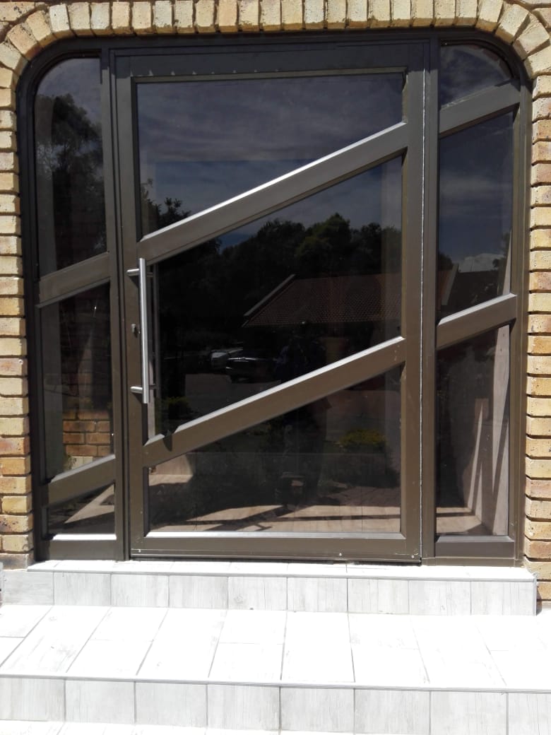 Arched aluminium pivoting entrance door with decorative glazing bars