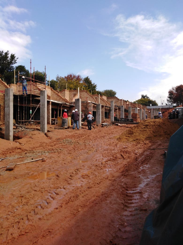 Row of brick complex units under construction with concrete columns and scaffolding