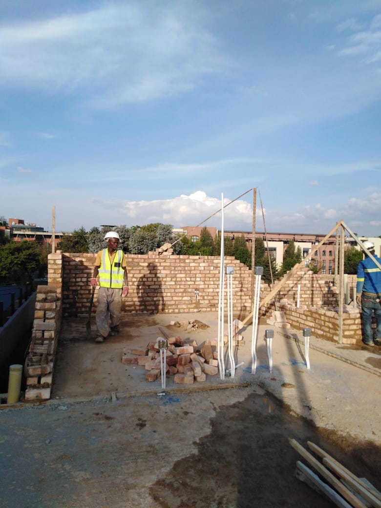 Worker on a brick-walled unit under construction with conduit set into the walls