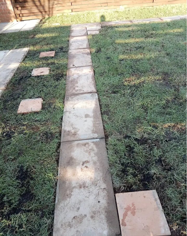 Straight paved garden walkway surrounded by newly laid lawn