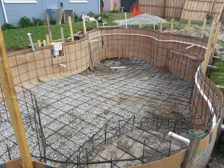 Brick-walled swimming pool under construction with reinforcement mesh over the floor and walls