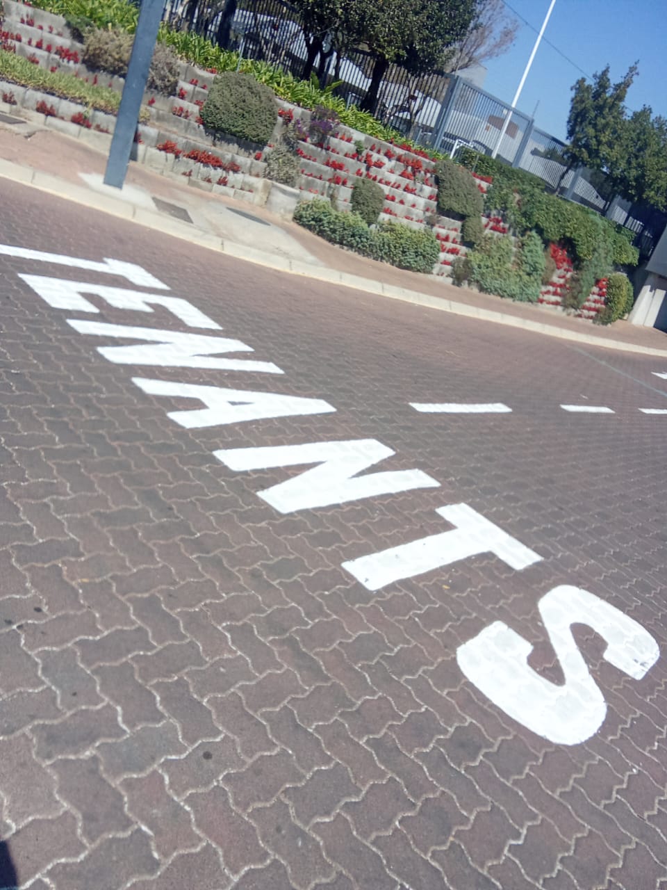 TENANTS painted in white road marking paint on block paving