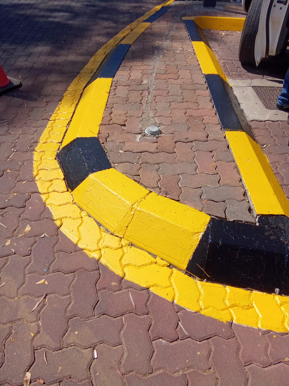 Kerbing painted in yellow and black hazard stripes on a paved traffic circle