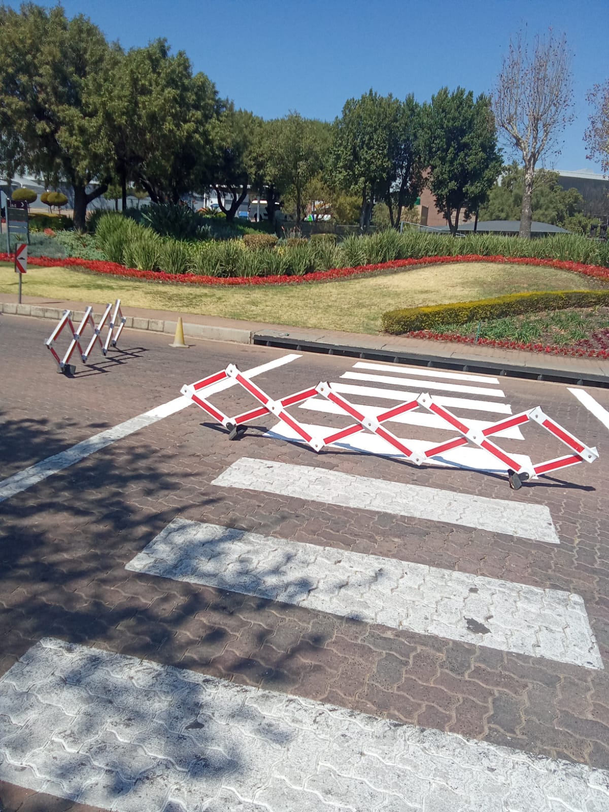 Painted pedestrian crossing and stop line on block paving with traffic barriers
