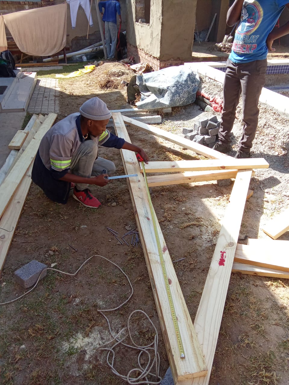 Carpenter measuring and marking timber roof beams on site