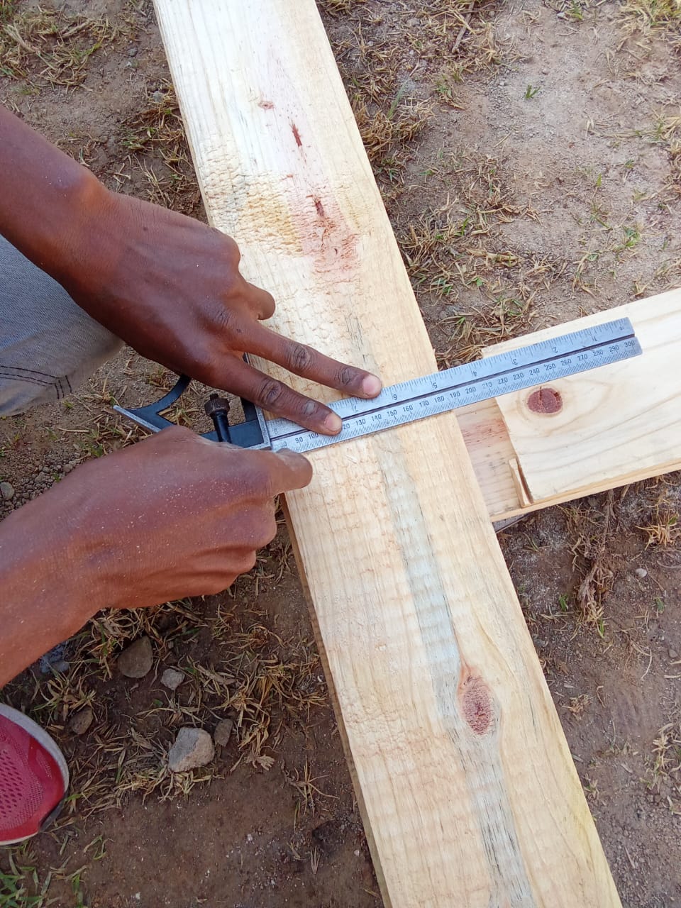Close-up of a combination square marking a cut line on a timber roof beam